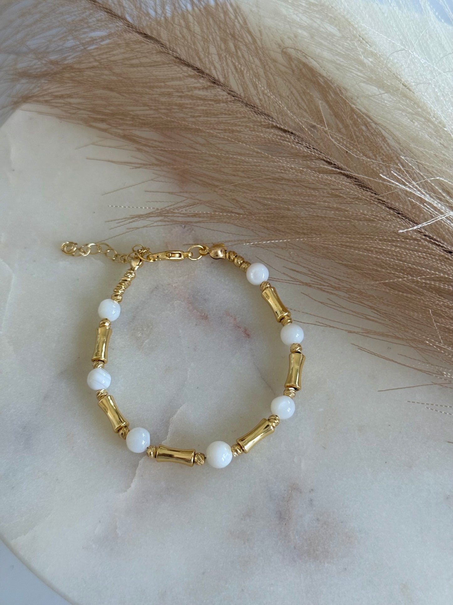 Armband mit weißen Steinperlen und goldfarbenen Akzenten